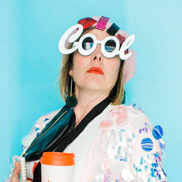Kara in giant white 'Cool' novelty glasses, holding a coffee