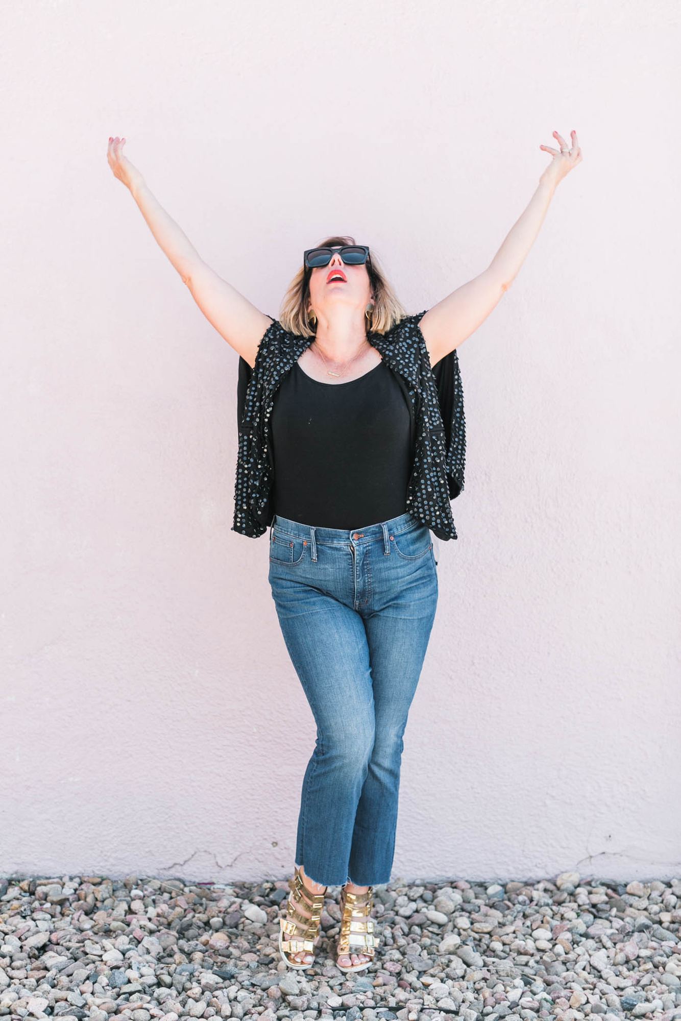 Kara with both arms raised against a pale pink wall