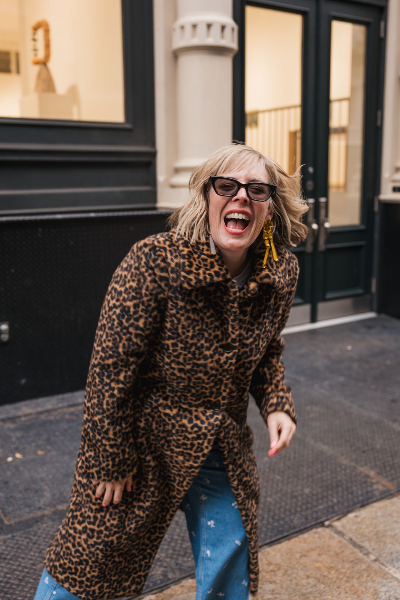 Kara laughing hard in a leopard coat on a New York street