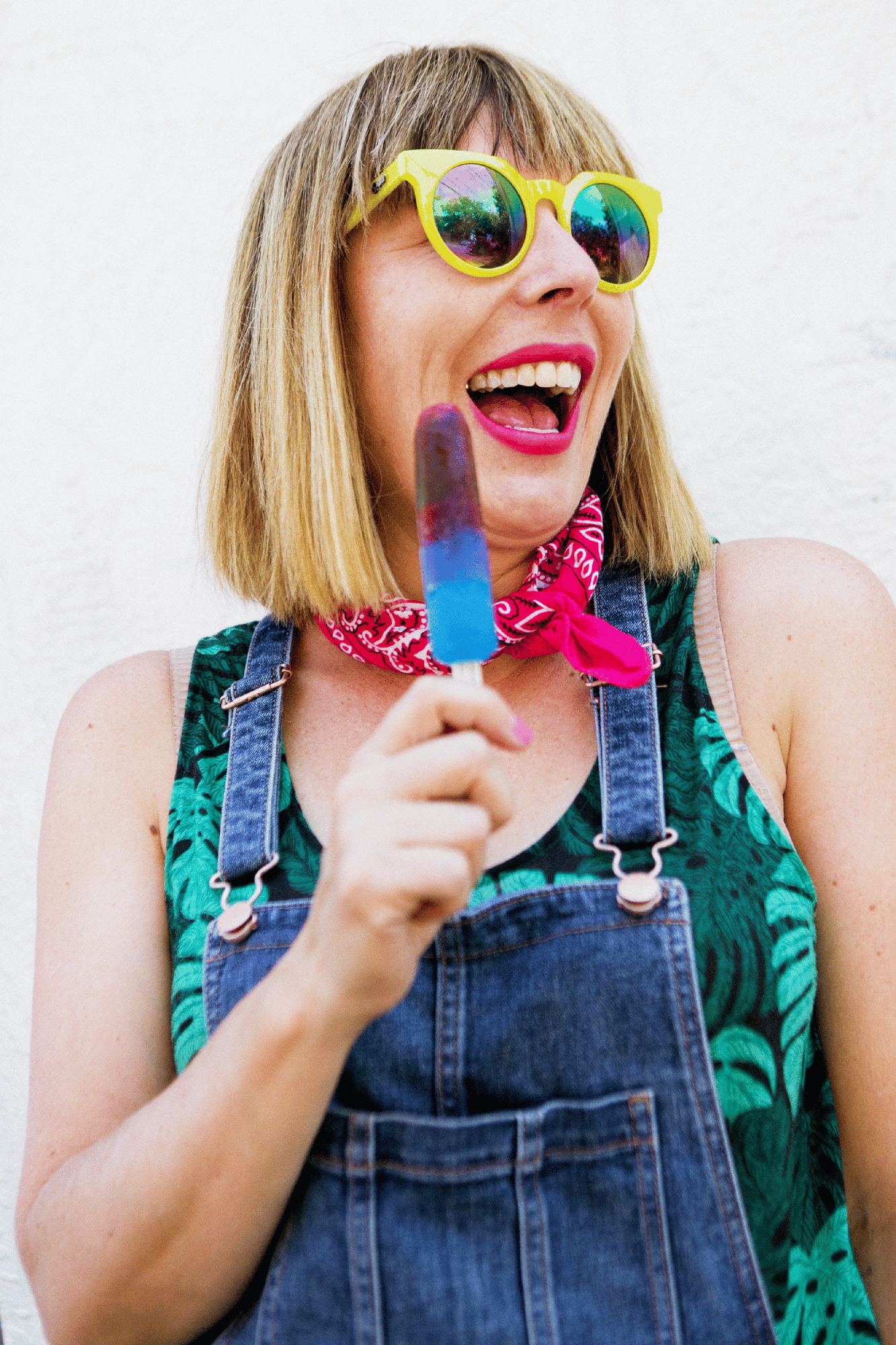 Kara in yellow sunglasses and overalls, delighted with a popsicle